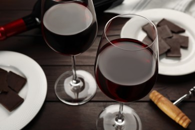 Tasty red wine and chocolate on wooden table, closeup