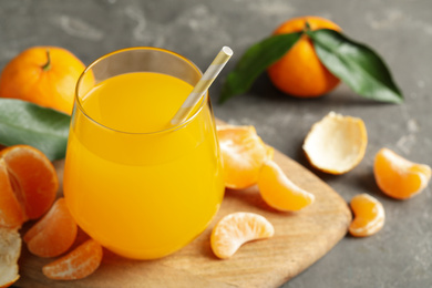 Photo of Fresh tangerines and glass of juice on grey table