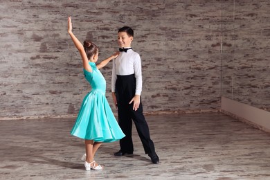 Beautifully dressed couple of kids dancing together in studio, space for text