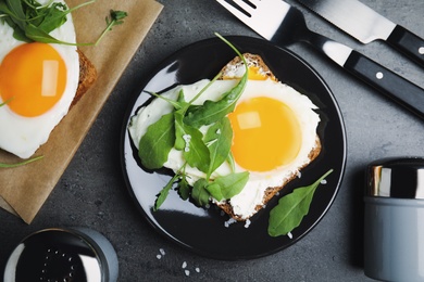 Delicious sandwich with arugula and fried egg on grey table, flat lay