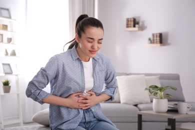 Young woman suffering from stomach ache at home. Food poisoning