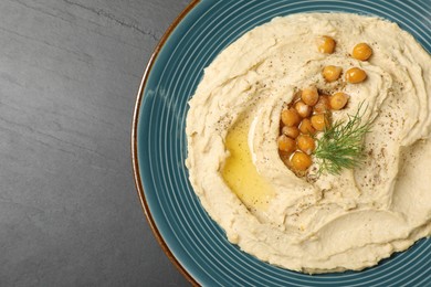 Plate of tasty hummus with garnish on black table, top view