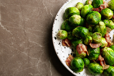 Delicious Brussels sprouts with bacon on marble table, top view. Space for text