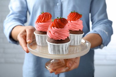 Photo of Woman holding dessert stand with sweet cupcakes, closeup
