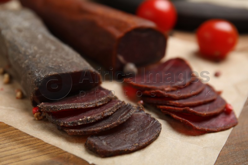 Delicious dry-cured beef basturma with peppercorns on wooden table, closeup