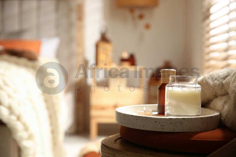 Burning candles on wooden chair in bedroom, space for text. Interior elements