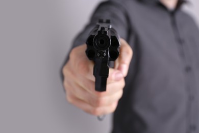 Man holding gun on grey background, closeup