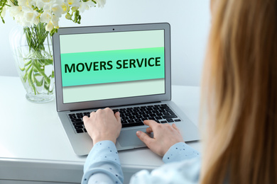 Woman using laptop to order movers service indoors, closeup
