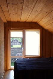 Window with roller curtains in bedroom on sunny day