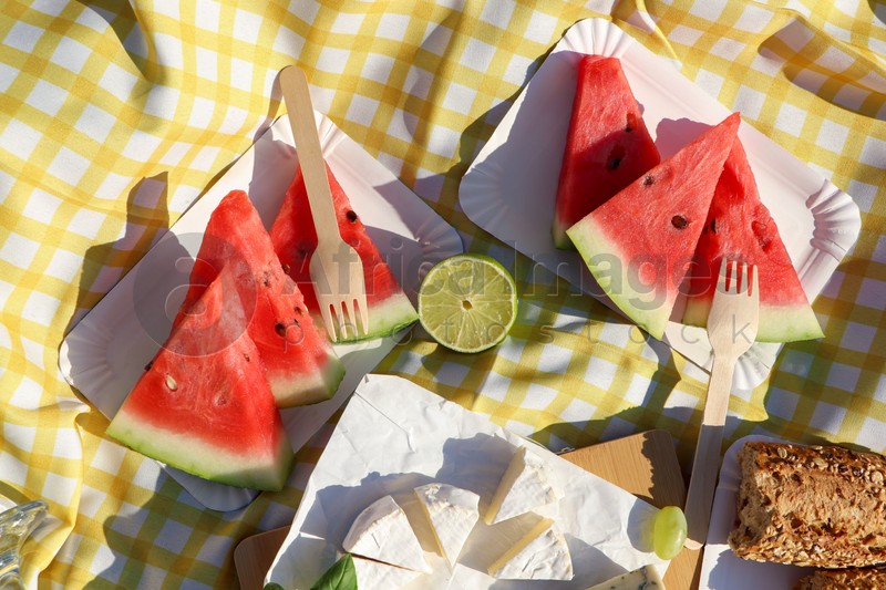 Delicious cheese, watermelon and bread on picnic blanket, flat lay