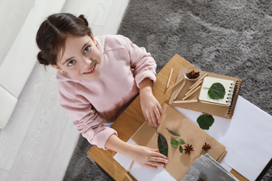Little girl working with natural materials at table indoors, top view. Creative hobby