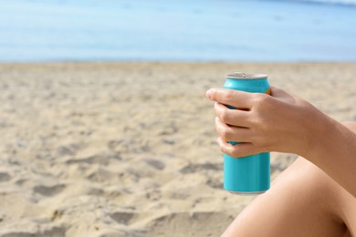 Photo of Woman holding aluminum can with beverage on beach, closeup. Space for text
