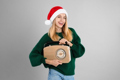 Happy woman with vintage radio on grey background. Christmas music