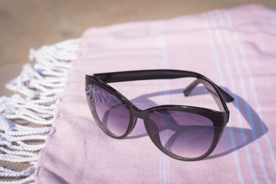 Photo of Stylish sunglasses on blanket outdoors, closeup. Beach accessories
