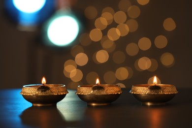 Photo of Lit diya lamps on dark table. Diwali celebration