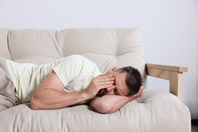 Photo of Sleepy man lying on sofa at home