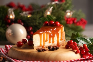 Photo of Tasty caramel cheesecake and Christmas decorations on table, closeup