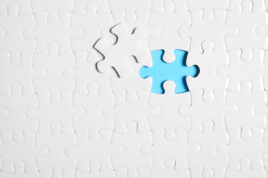 Blank white puzzle with separated piece on light blue background, top view