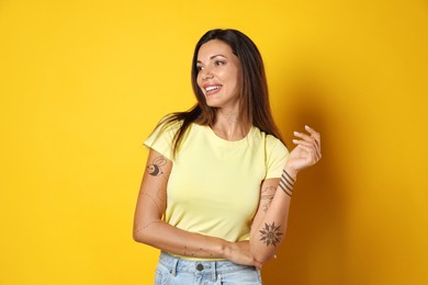 Image of Attractive woman with beautiful tattoo sketches on yellow background