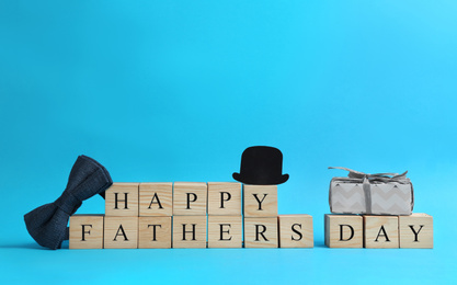 Wooden cubes with phrase HAPPY FATHER'S DAY on light blue background