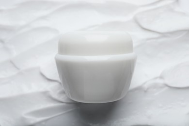 Jar on smeared white body cream, top view