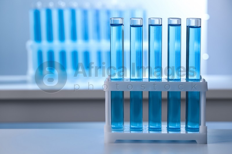 Test tubes with reagents on table in laboratory, space for text