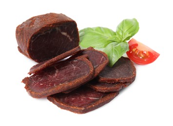 Delicious dry-cured beef basturma with basil and tomato on white background