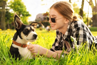 Photo of Teenage girl with her cute dog resting on green grass in park