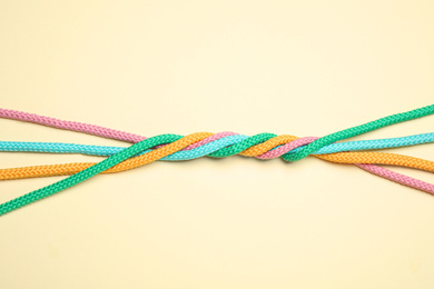 Twisted colorful ropes on beige background, top view. Unity concept