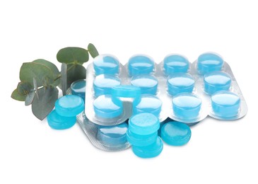 Many light blue cough drops and eucalyptus on white background