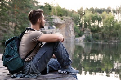 Young man on wooden pier near lake. Camping season