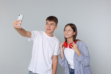 Photo of Teenage boy and girl taking selfie on light grey background