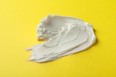 Smear of delicious cream cheese on yellow background