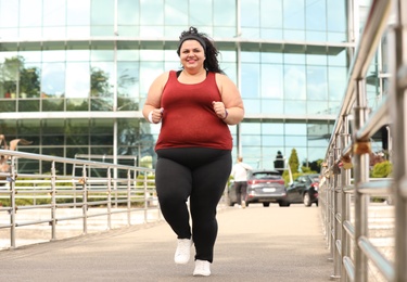 Beautiful overweight woman running outdoors. Fitness lifestyle