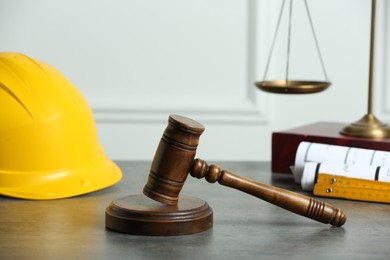 Photo of Construction and land law concepts. Judge gavel, scales of justice, construction helmet and drawings on wooden table