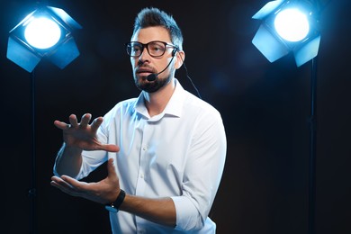 Photo of Motivational speaker with headset performing on stage. Space for text