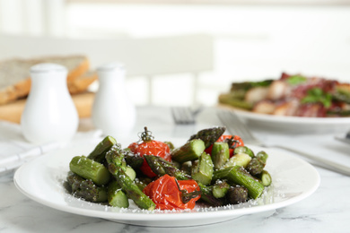 Oven baked asparagus with cherry tomatoes on white plate
