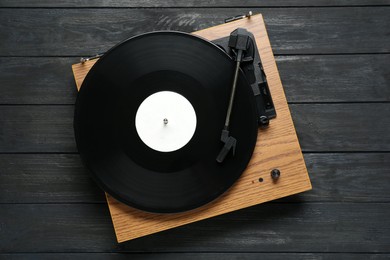Turntable with vinyl record on black wooden background, top view