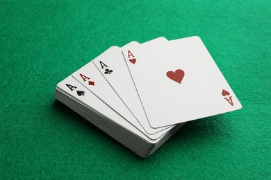 Photo of Four aces playing cards on green table, closeup. Poker game