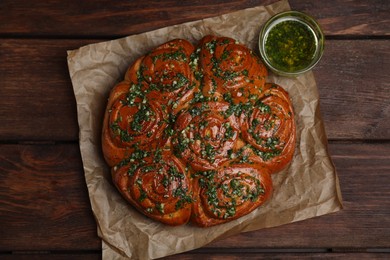 Traditional Ukrainian garlic bread with herbs (Pampushky) and aromatic oil on wooden table, flat lay