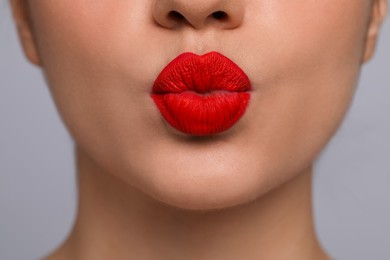 Closeup view of beautiful woman puckering lips for kiss	on grey background