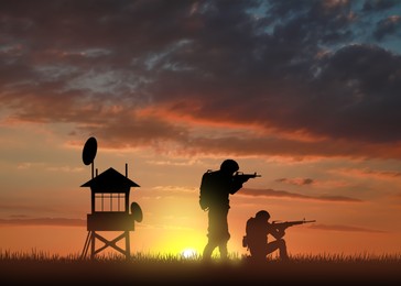 Silhouettes of border guards at post outdoors in evening