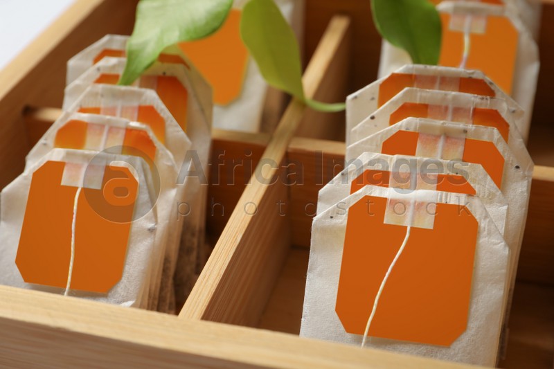 Photo of Paper tea bags with tags in wooden box , closeup