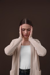 Woman suffering from headache on brown background. Cold symptoms