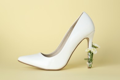 Stylish women's high heeled shoe with beautiful flowers on pale yellow background
