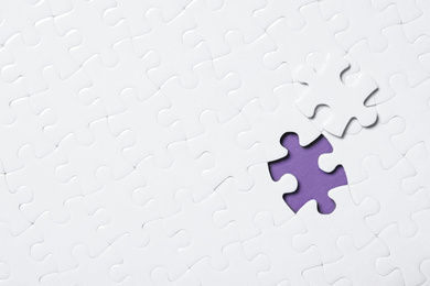 Blank white puzzle with separated piece on purple background, top view. Space for text