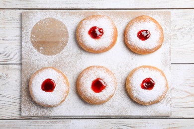 Hanukkah doughnuts with jelly and sugar powder on wooden table, flat lay