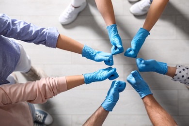 Group of people in blue medical gloves showing thumbs up indoors, top view