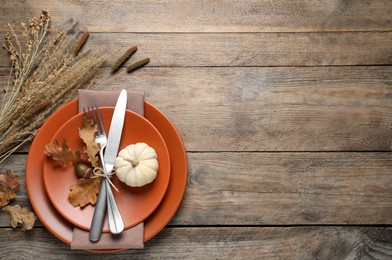 Festive table setting with autumn decor on wooden background, flat lay. Space for text