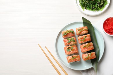 Tasty sushi rolls with salmon served on white wooden table, flat lay. Space for text